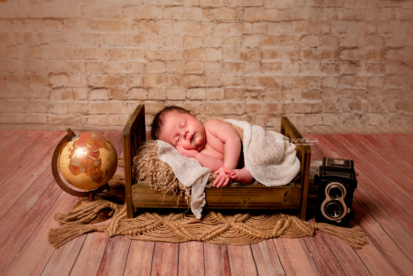 Nouveau-né vintage dormant paisiblement dans un petit lit, près d'un globe et d'appareil photo. Joséphine Bot Photographe