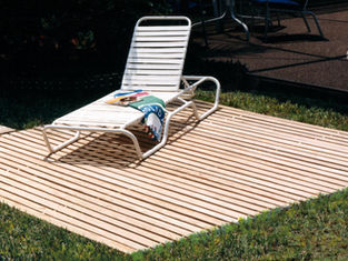Mister Boardwalk® Roll-Out Deck used as a poolside lounge area with chair beside a backyard swimming pool.