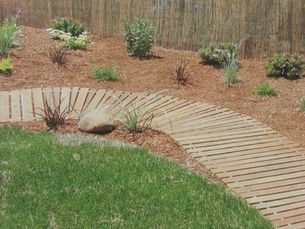 Curved Mister Boardwalk® Roll-Out Boardwalk creating an attractive path through a landscaped backyard.