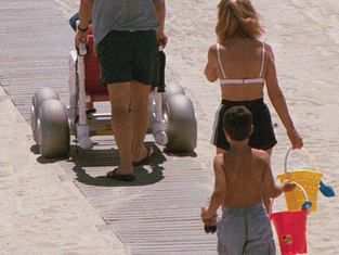 Family using a beach boardwalk with a beach wheelchair to access the shoreline.