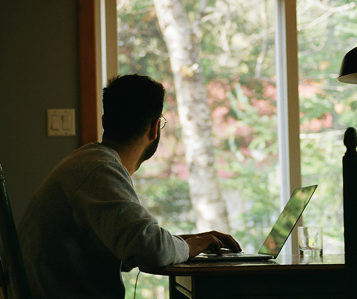 man loooking at the window with a laptop contemplating.jpg