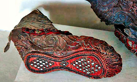 Ornately beaded leather shoe, with red cloth on the sole,.