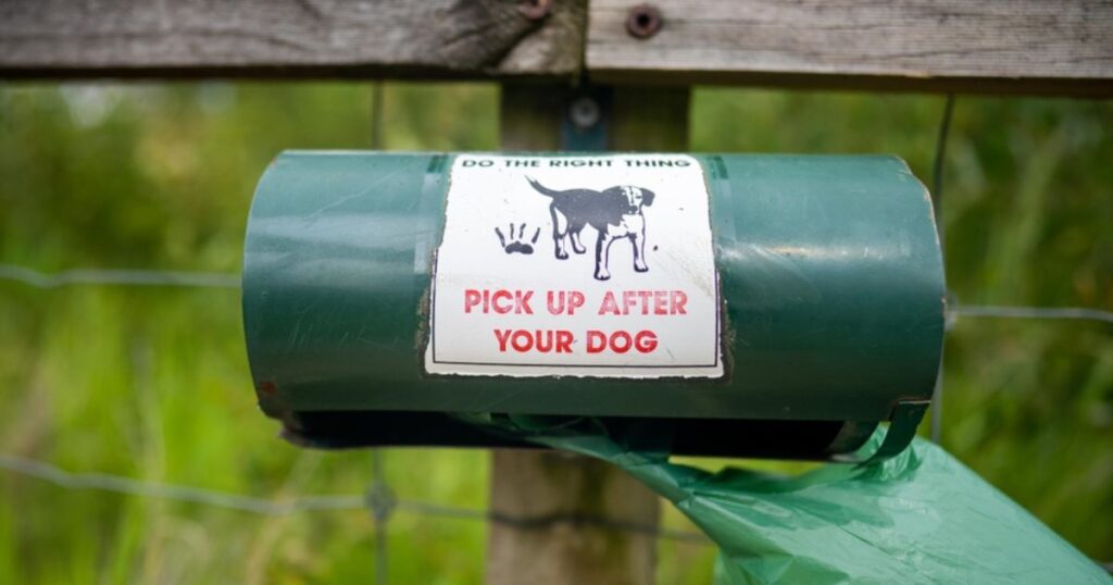dog poop bag holder on a fence that reads 'do the right thing, pick up after your dog'