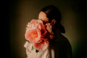 woman hiding behind a big luscious pink flower