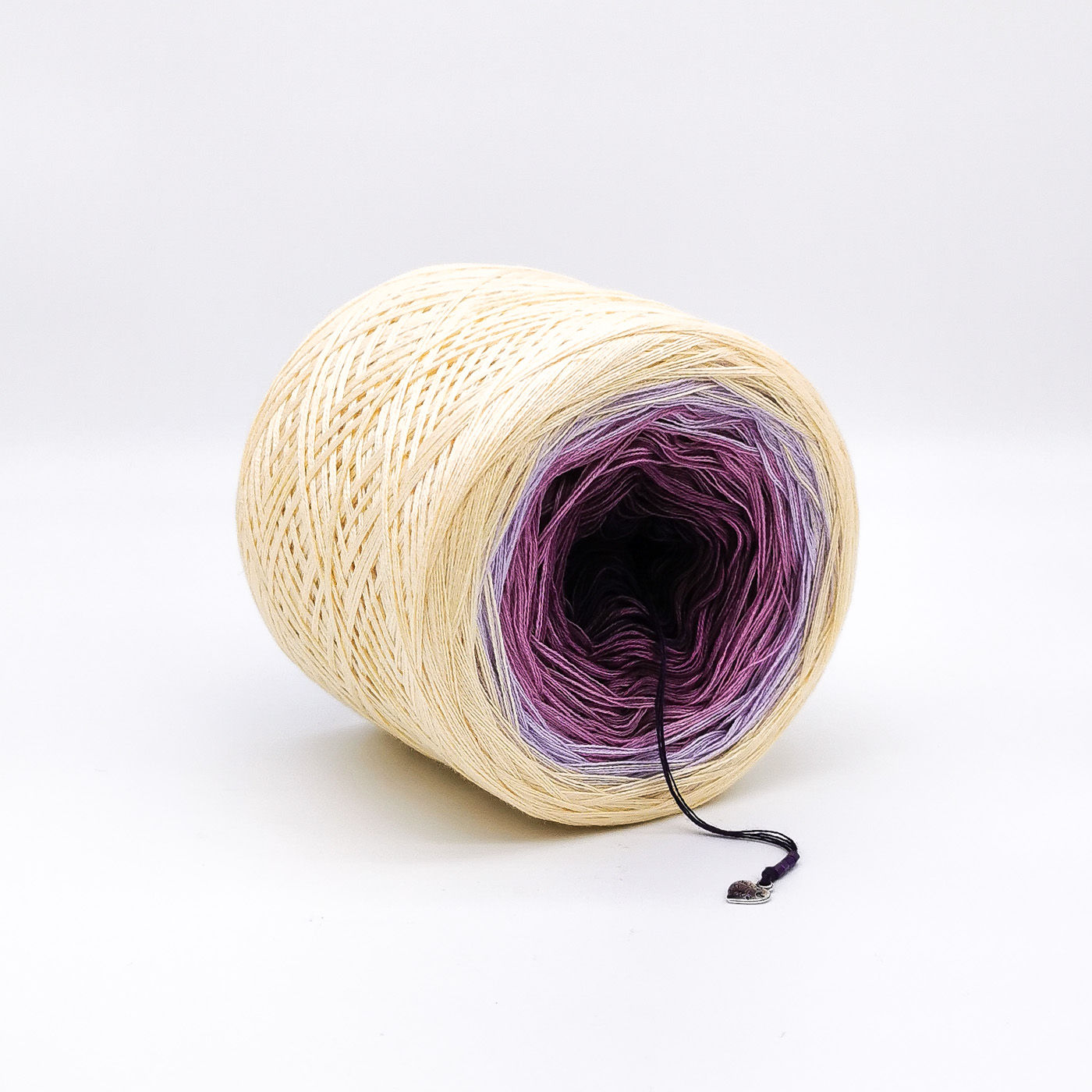 Cream, lilac, purple and black yarn cake on a white background