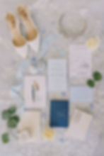 wedding flat lay with wedding invites, shoes, and rings