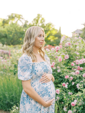 a mother in a rose garden holding her baby bump