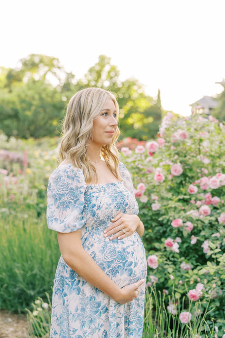 a mother in a rose garden holding her baby bump