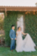 bride and groom in front of greenery wall