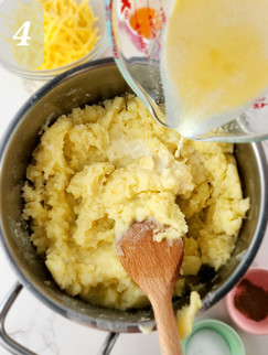 Slowly pour the warm milk-butter mixture in the mashed potatoes while stirring continuously to achieve a creamy consistency.