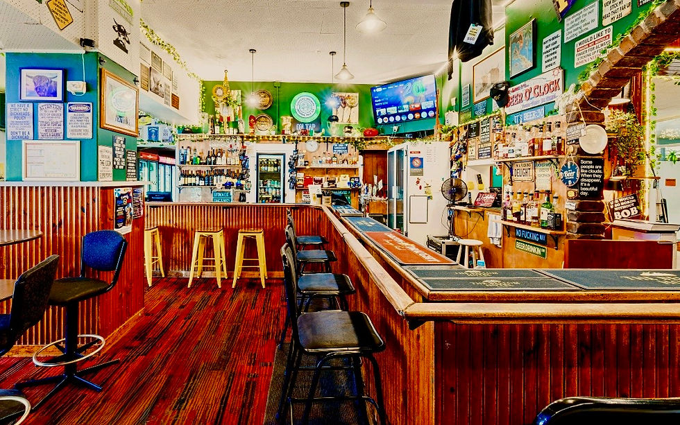Close-up view of a publican’s hands wiping down a timber bar in a quiet country pub.