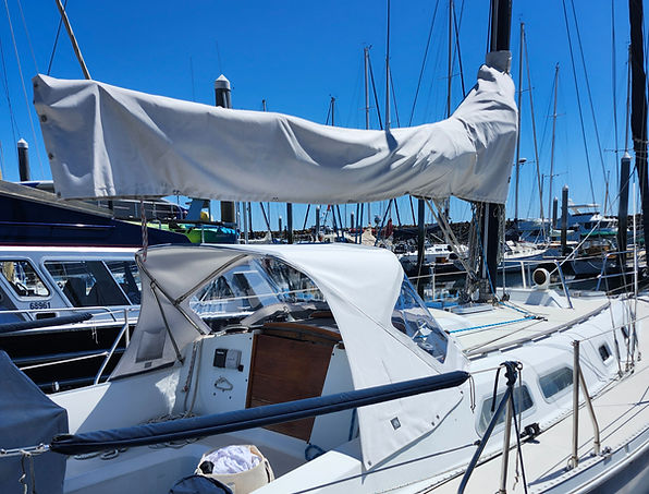 a sailboat with sail cover and dodger at the dock