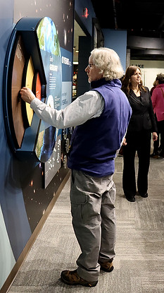 Visitor in the new Discover Northeast Michigan History Exhibit turning thewheel to learn more about geology of the area.