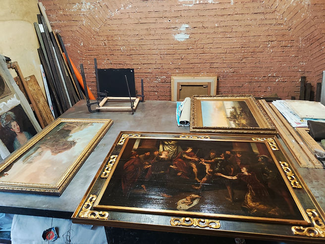 Dipinti con cornici e tavoli in un laboratorio storico e di arte