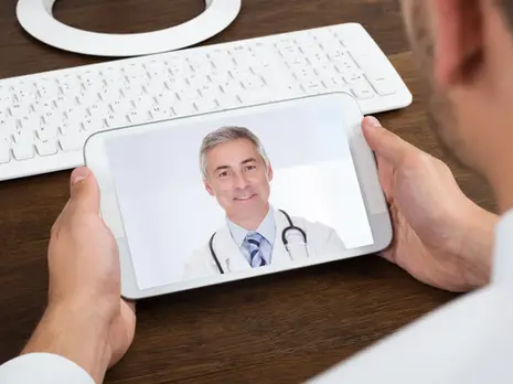 Image of someone holding a tablet looking at a doctor on camera.