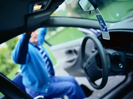 A senior man getting behind the wheel of a car.