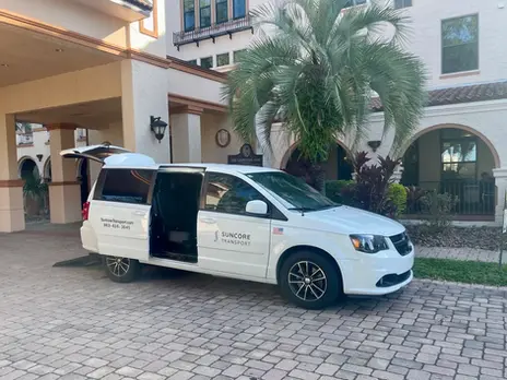 Image of a white suncore transport van picking up passengers from a facility.