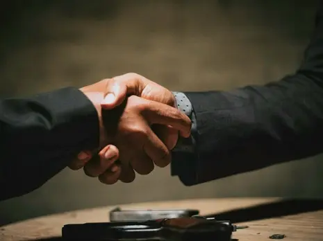Image of two hands shaking in suit attire.