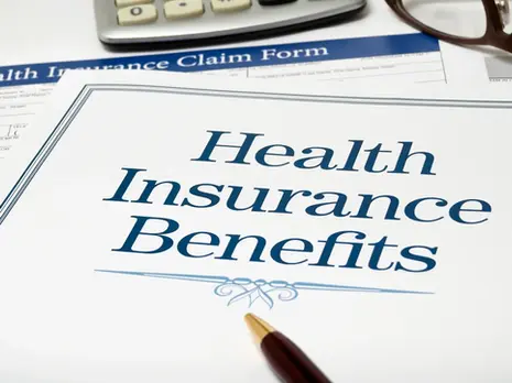 Health Insurance Benefits document with pen, glasses, and calculator on a desk. Blue text on a white background, suggesting organization.