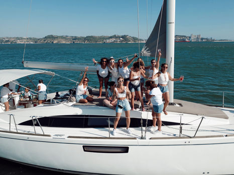 Group of friends celebrating a bachelor and bachelorette party aboard a private catamaran on the Tagus River in Lisbon.