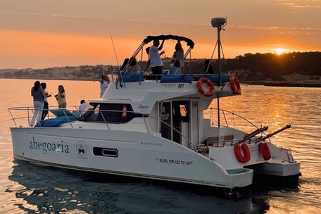 Catamaran Xuxu da Royal Marine ao pôr do sol no rio Tejo, com Lisboa ao fundo