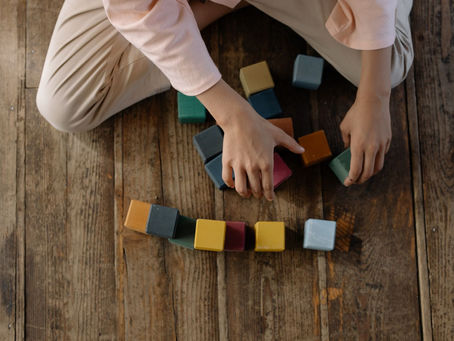 Child stacking colourful blocks on a wooden floor