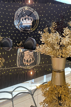 Luxurious Moët & Chandon Christmas setup with golden bar, festive string lights, and elegant black-and-gold holiday decor.