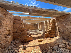 Structural restoration underway inside a stone building, showing newly installed concrete beams and scattered debris.