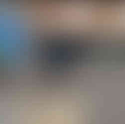 Close view of a newly planted Black Muscat grapevine mulched with straw next to a metal grid trellis beside the porch; blue barrel and black tub nearby.