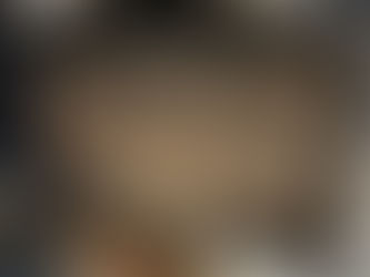 Curved glass door of a wood-burning stove coated with smoke residue and ash specks in a rustic interior setting.