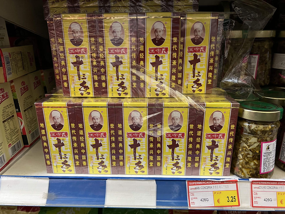 Store shelf displaying boxed Shi San Xiang 13 Spices products with Chinese text and a portrait, alongside jars of preserved food.