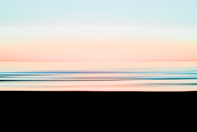 A minimalist long-exposure seascape featuring soft horizontal bands of pastel pink, peach, and aqua drifting across the horizon. The blurred ocean waves create a serene, abstract composition that evokes calm and tranquility, highlighting the gentle transition of light over the water at dusk in a modern fine-art style.
