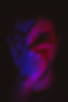 Man covering his face with his hand, illuminated by red and blue light
