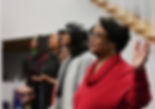 Woman and congregation worshiping together with hands lifted in a church service