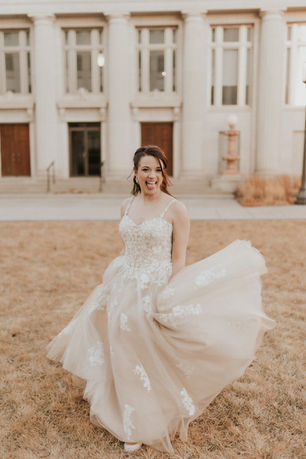 Joyful bride twirling in a flowing white wedding dress outdoors