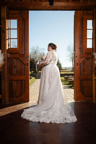 Bride in white wedding dress looking out open doors