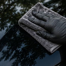 Professional hand removing tree sap from a black car.