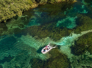 Aerial view of small boat on a crystal clear river.