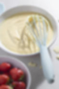 custard cooking in a pan with strawbserries on the side