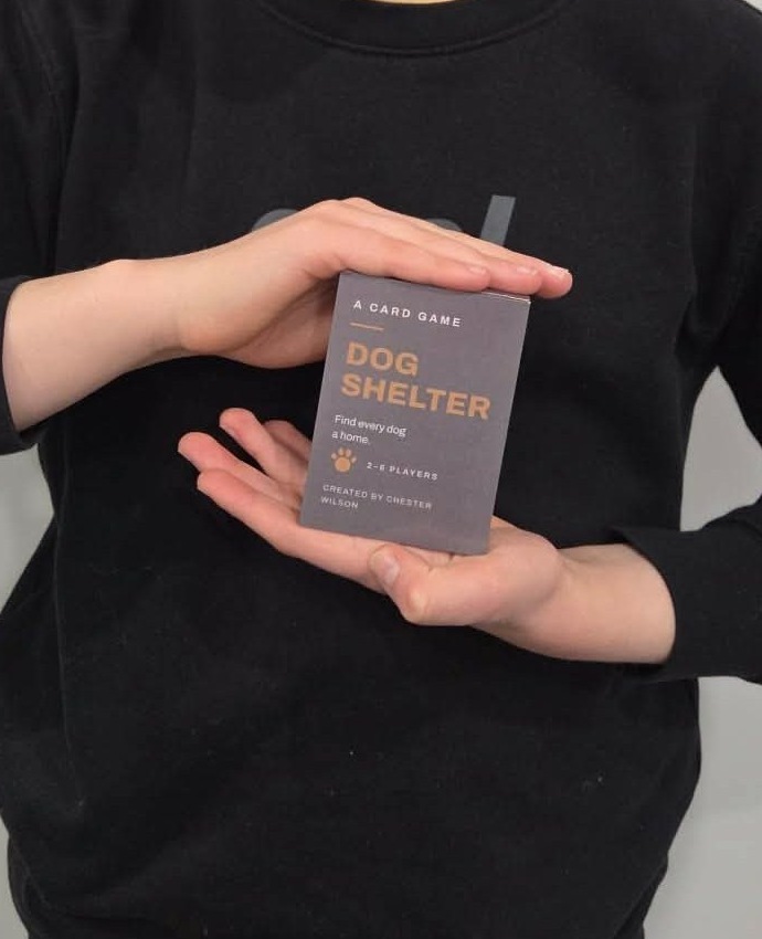 A finished copy of the Dog Shelter card game held in two hands.