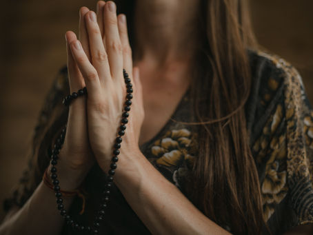 Hands in prayer with a black beaded bracelet.