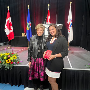 Two proud brown women — Mayor and guest speaker, pose together, sharing a common background. 