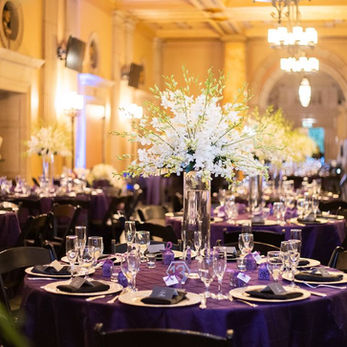 Picture of elegant dining room guest tables with tall floral centerpieces in an historic ballroom