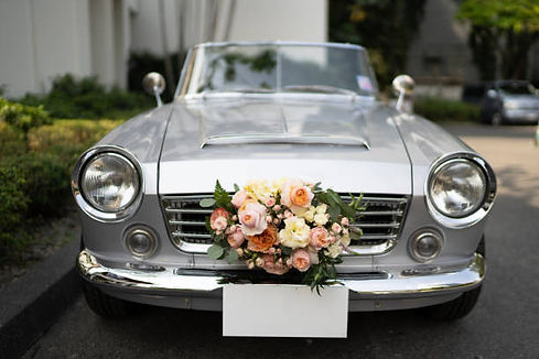 silver vintage car with floral wedding wreath on the grill