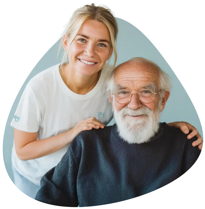 Junge Frau im weißen Shirt umarmt lächelnden älteren Herrn mit Bart und Brille..