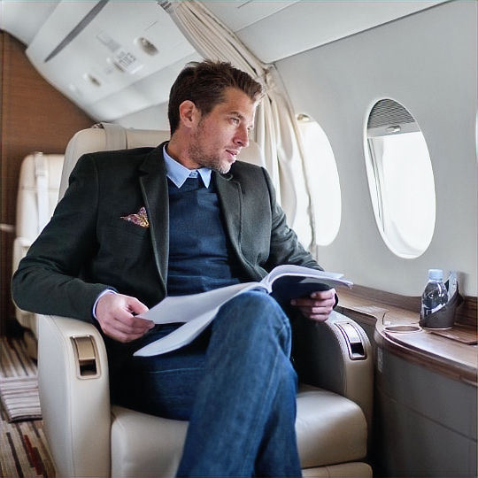 Executive man in a private jet, reading documents with a calm and focused demeanor, representing luxury and security.