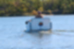 Small motorized paddle boat for two gliding on water; a compact portable boat and great gift for boaters who love lake toys.