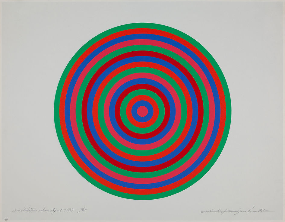 Un cercle composé de multiples anneaux colorés est imprimé au centre d’une feuille de papier horizontale. À partir d’un petit cercle magenta au centre, des anneaux aux couleurs vives irradient vers l’extérieur pour former un motif variable de magenta, bleu, cramoisi, vert et rouge.