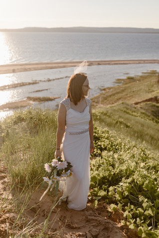 lesbian bride standing on a large dune covered in greenery