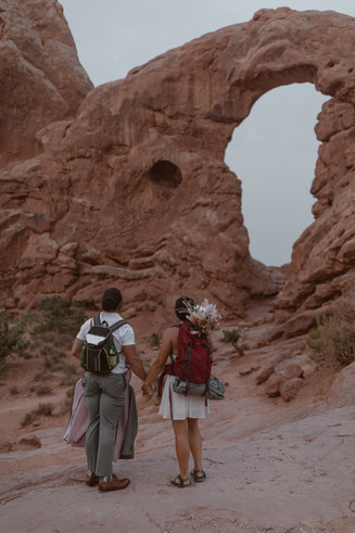 bride and groom hiking on their elopement in arches national park